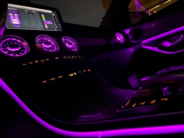Bordcomputer eines Mercedes mit geöffneter Farbauswahl für die Ambientebeleuchtung, Lüftungsdüsen leuchten magenta