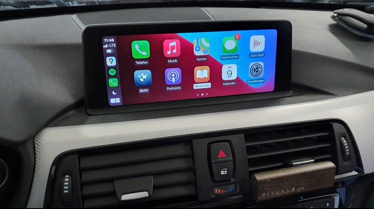 Nachgerüstetes Apple CarPlay auf dem Display eines BMW mit Telefon-, Musik- und Karten-App